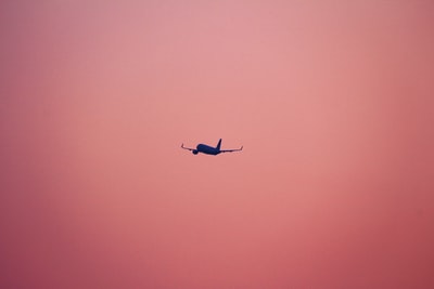 粉红色背景下飞行的飞机